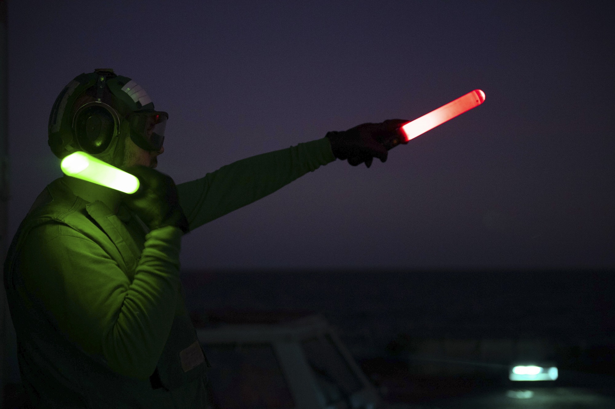 Aviation Maintenance Administrationman Robert Murdolo signals to the pilots of an MH-60R Sea Hawk helicopter Dec. 15, 2020, during night flight operations aboard the guided-missile cruiser USS Princeton (CG 59) in the North Arabian Sea.