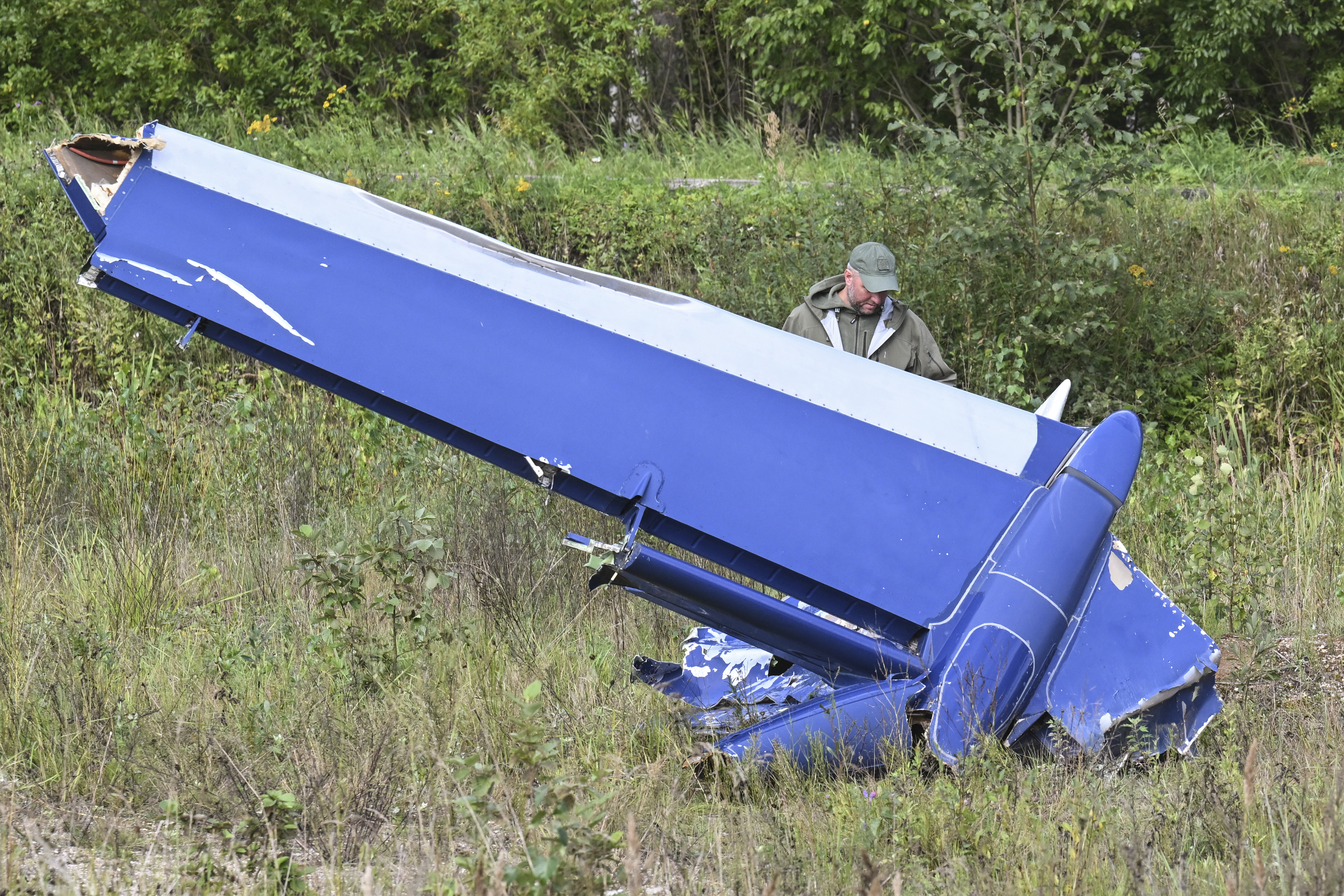 A Russian serviceman inspects a part of a crashed private jet near the village of Kuzhenkino, Tver region, Russia, Thursday, Aug. 24, 2023.